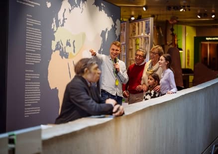 Bei Führung für Familien zeigt Museumsbegleiter auf Verbreitungskarte