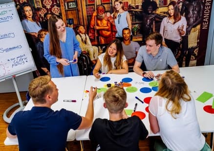 Erwachsene sitzen um Tisch bei Firmen und Teamevent im Seminarraum