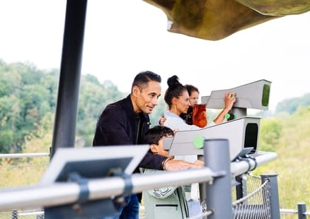 Familie schaut durch virtuelles Fernrohr auf Erlebnisturm Höhlenblick