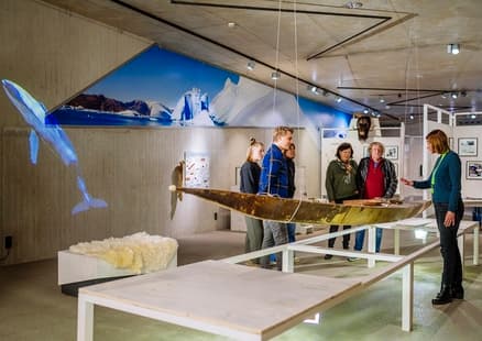 Besuchende bei Führung vor dem Kajak in der Sonderausstellung Eiszeitreise Grönland
