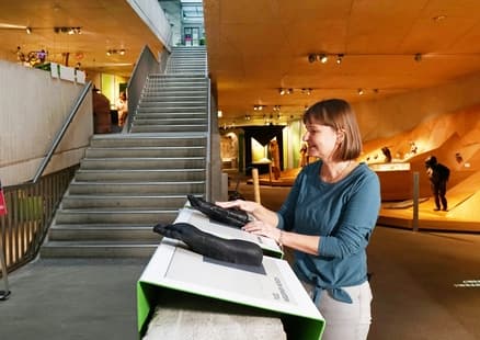 Blinde Frau ertastet einen menschlichen und einen Affenfuß in der Ausstellung