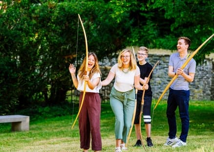 Erwachsene mit Bögen beim Bogenschießen bei Firmen und Teamevent