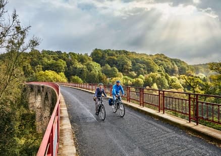 Erwachsene fahren über Viadukt auf PanoramaRadweg niederbergbahn
