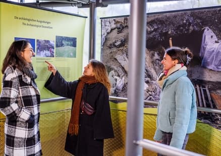 Erwachsene neben Infotafeln über Fundstelle am Erlebnisturm Höhlenblick