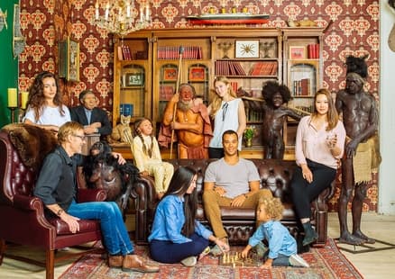 Familie sitzt auf Sofa neben Menschen Nachbildungen in Ausstellung