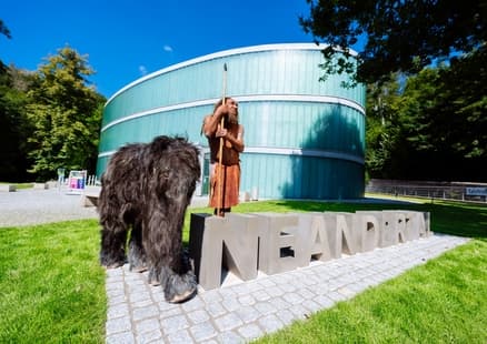 Neanderthaler MR N und Tinka stehen beim Neandertal Schriftzug vor Museum
